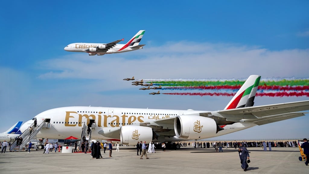 Interior of an exhibition hall at the Dubai Airshow, bustling with industry professionals and elaborate displays.