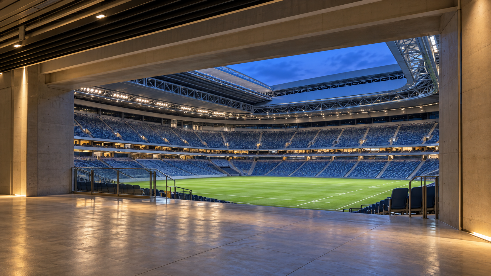 A view from the stadium concourse through to an empty rugby pitch at dusk